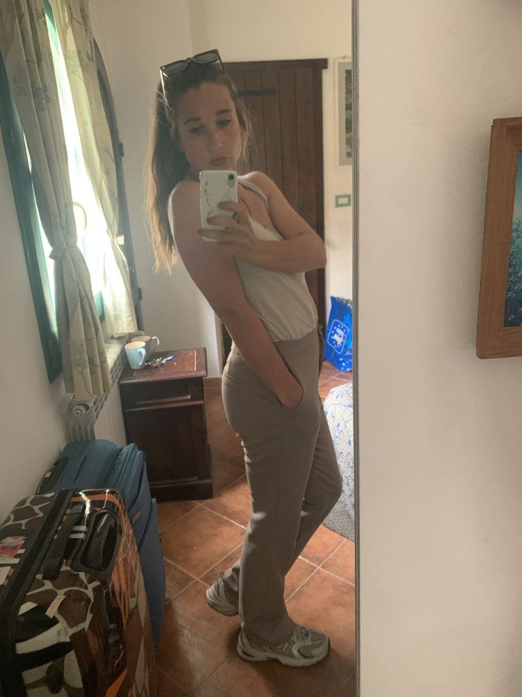 Alina in weißem Top und taupefarbener Hose vor dem Spiegel